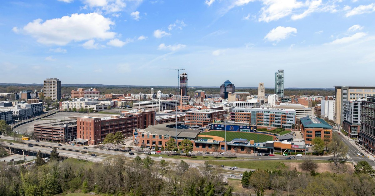 Aerial photo showing downtown Durham's vibrant skyline and cityscape on a sunny day.