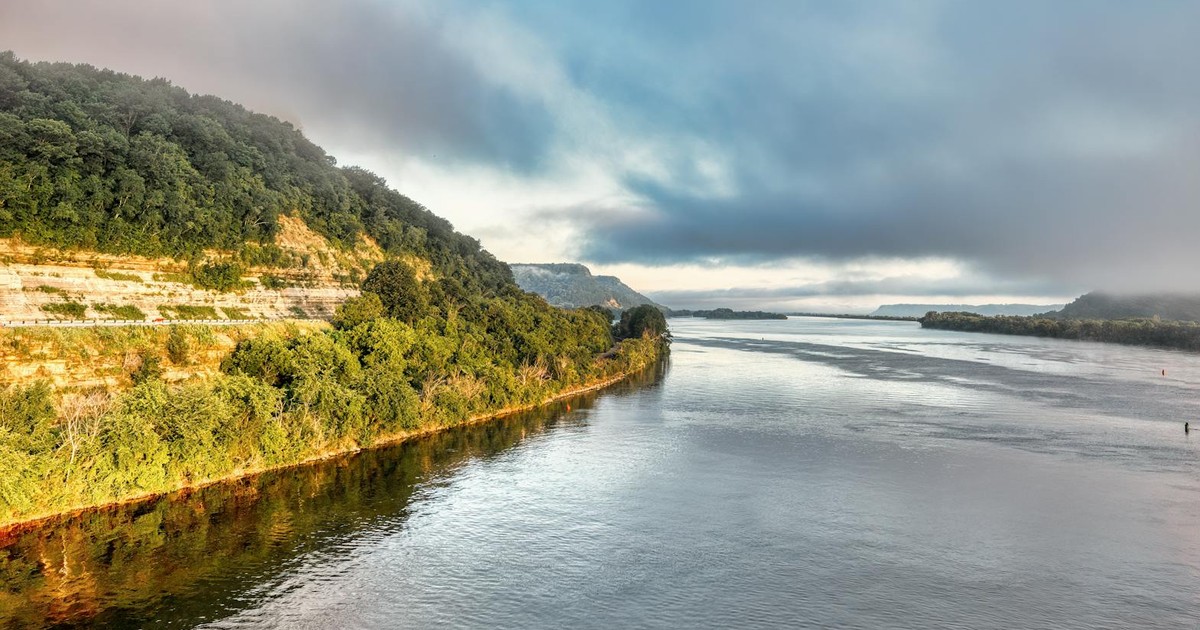 Breathtaking view of the Mississippi River's lush banks under cloudy skies in Minnesota.