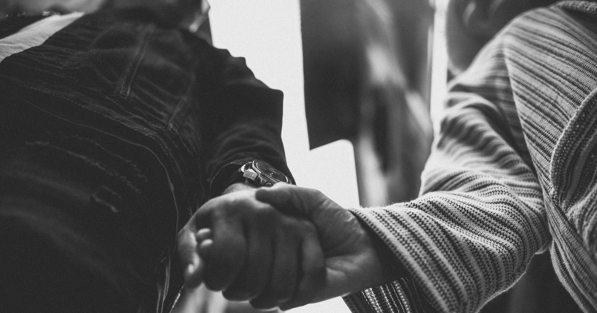 Black and white close-up of a couple holding hands, symbolizing connection.
