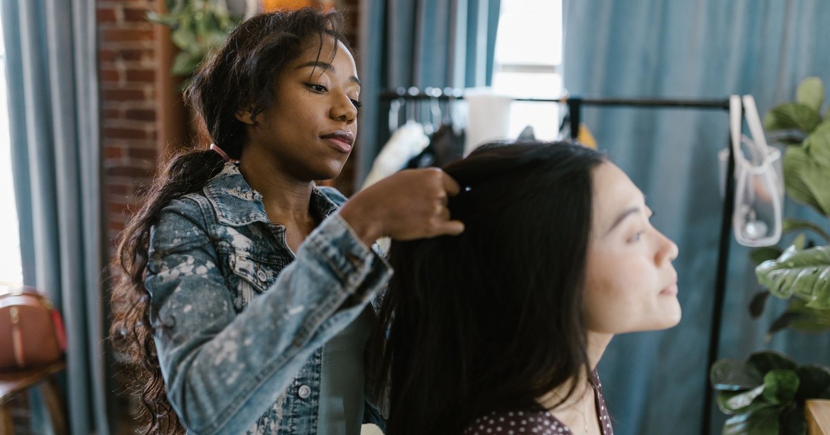 Two young women enjoying a fun hairstyling session at home, capturing moments of friendship.