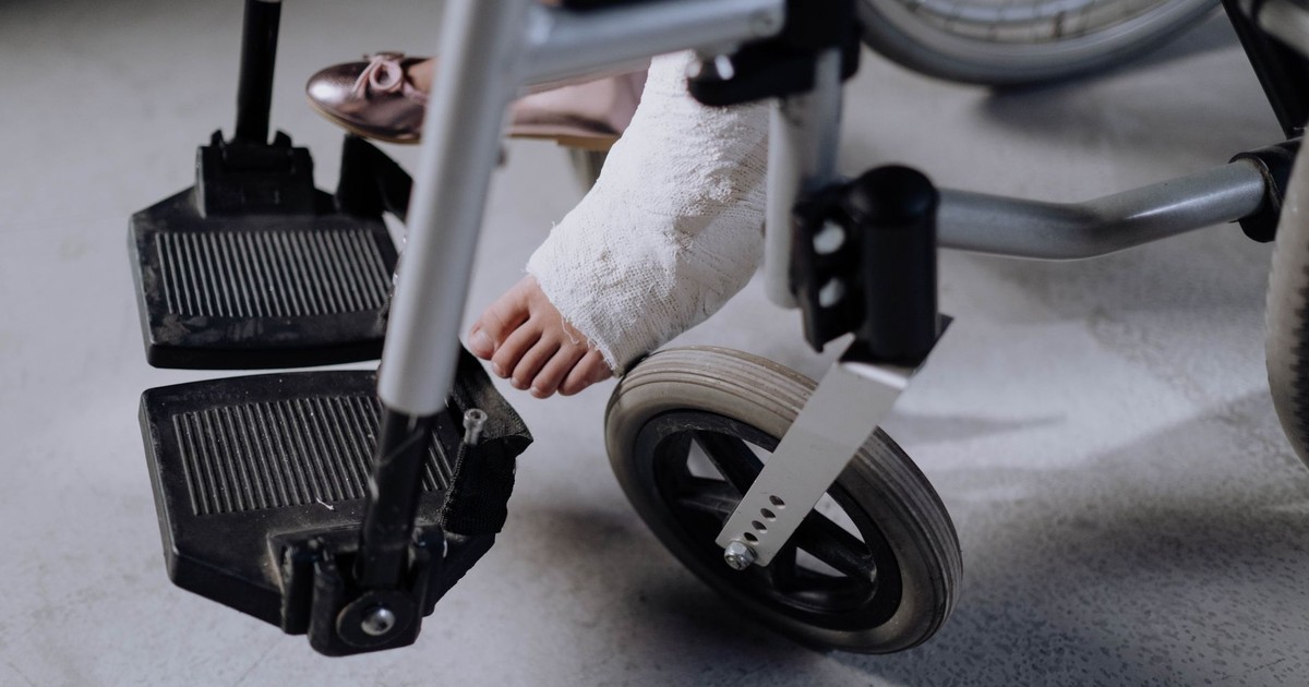 Close-up of an injured foot in a cast resting on a wheelchair, indoors.