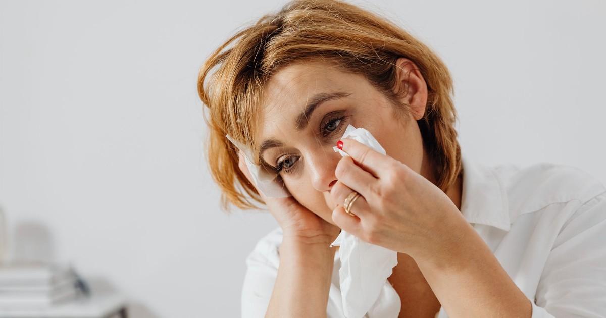 Portrait of woman holding tissue, expressing emotion, wiping tears.