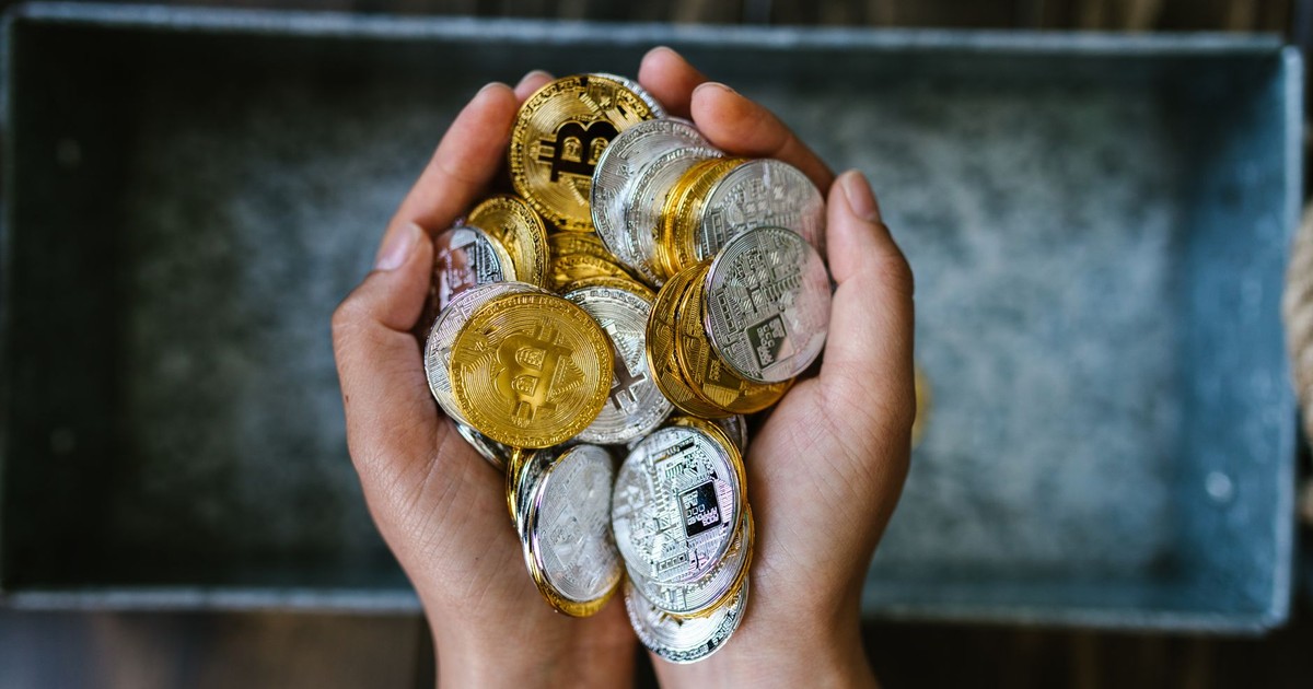 Close-up of hands holding gold and silver cryptocurrency coins, symbolizing digital investment.