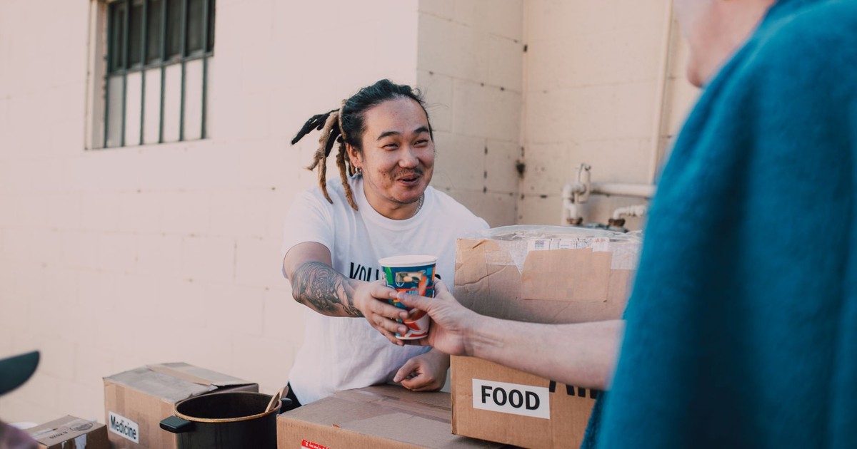 A volunteer handing out food and drinks at a charity event to support community causes.