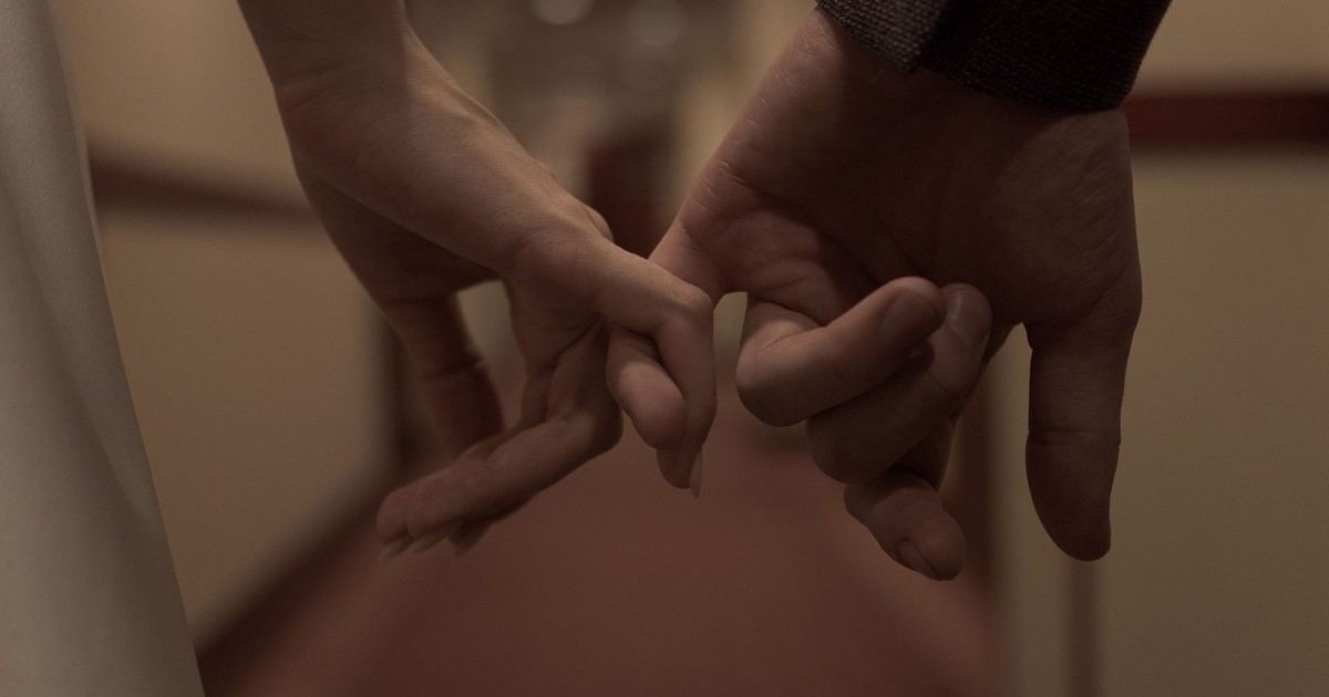 Tender close-up of two hands holding each other, symbolizing love and connection.