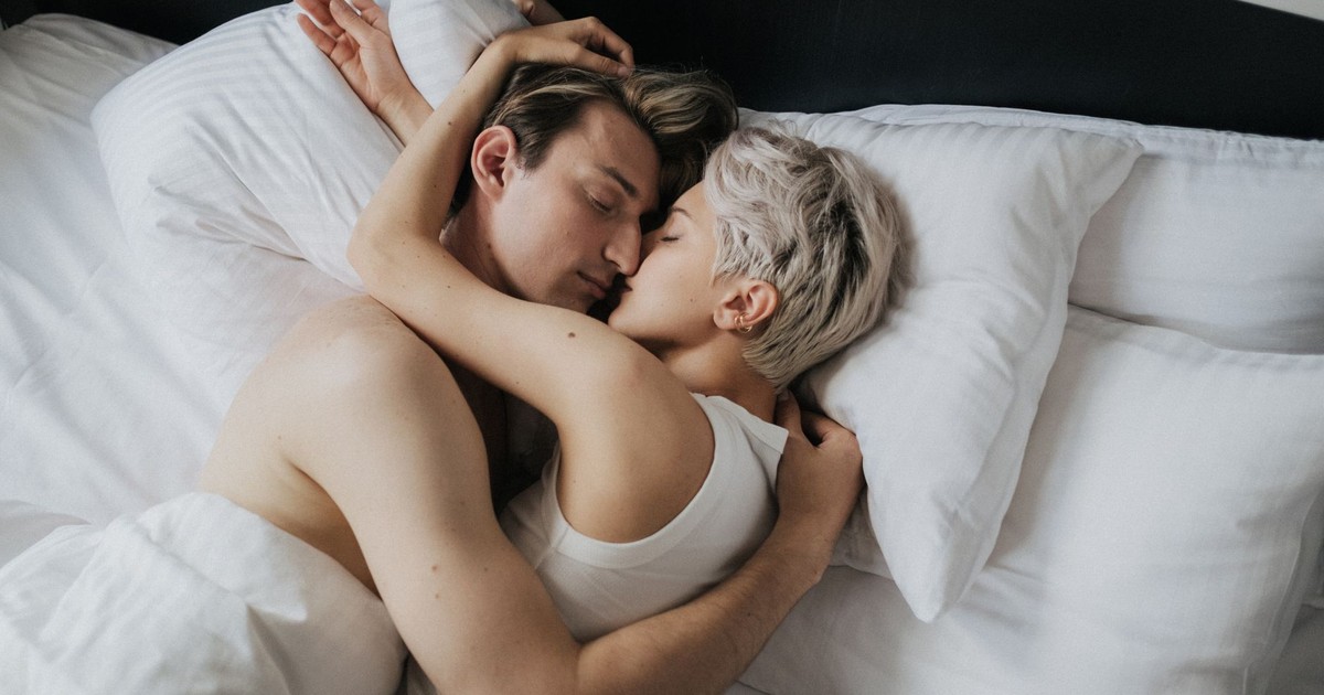 A close-up of a couple in an affectionate embrace while lying in bed.