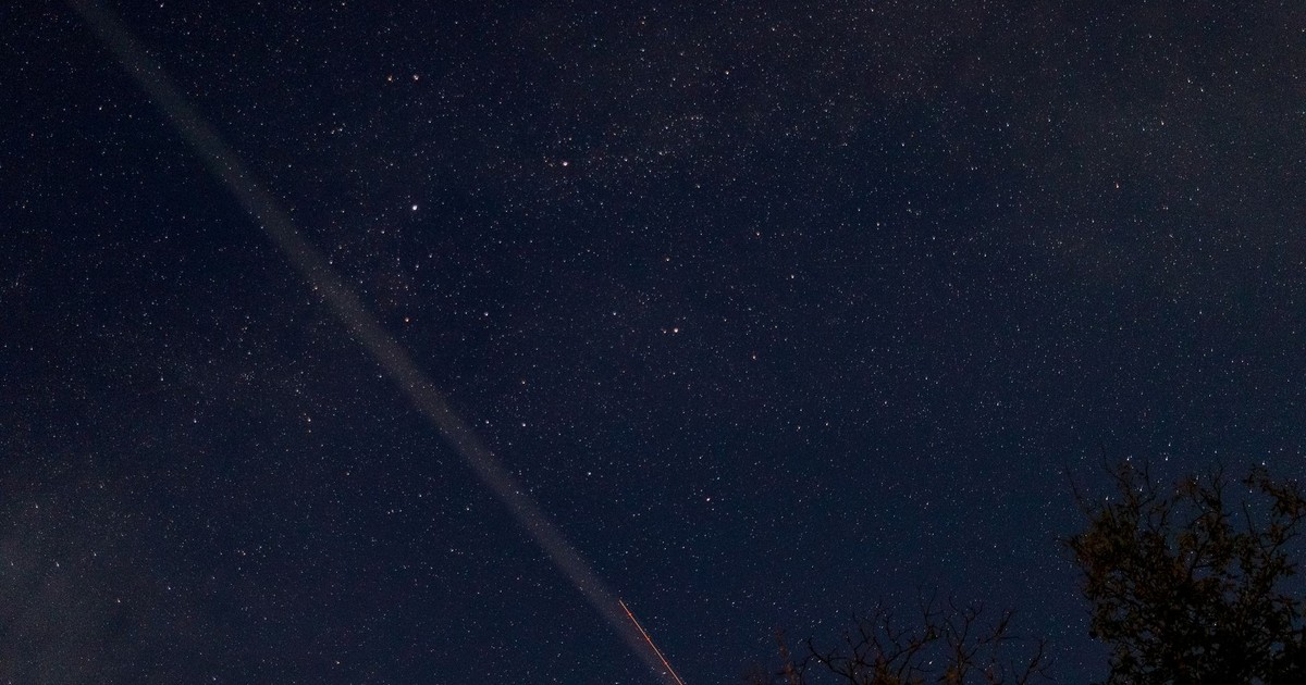 A breathtaking view of a starry night sky with a visible meteor streaking across, captured outdoors.