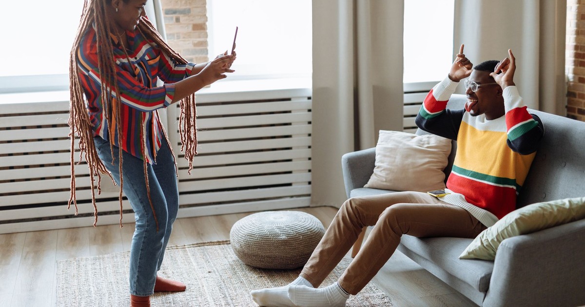 A couple enjoying playful photography in their cozy, sunlit living room.