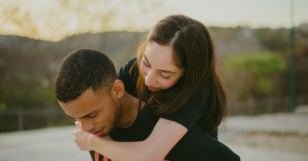 Young couple joyfully embracing outdoors on a sunny day, symbolizing love and togetherness.