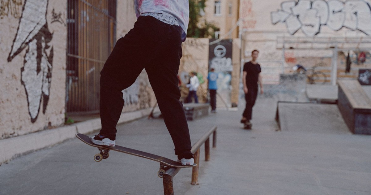 A skateboarder performs a thrilling trick on a rail at an urban skate park adorned with graffiti art.