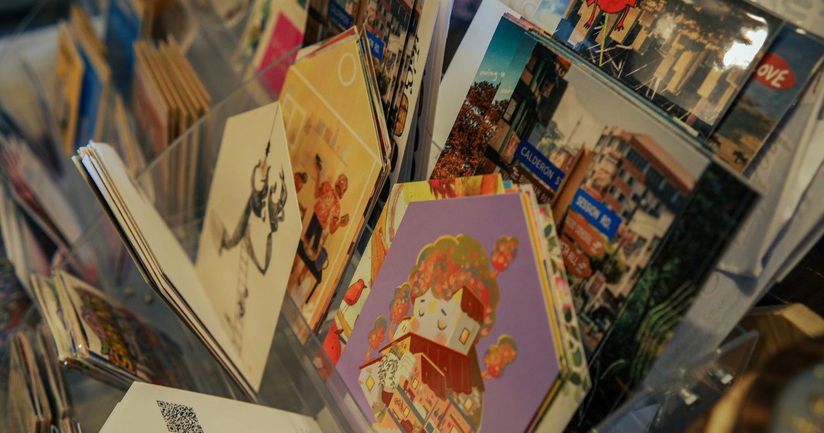 A colorful assortment of postcards featuring art and scenic views displayed on a rack.