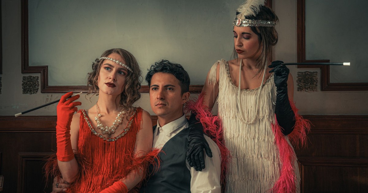 Elegantly dressed trio in 1920s vintage attire with glamorous accessories indoors.