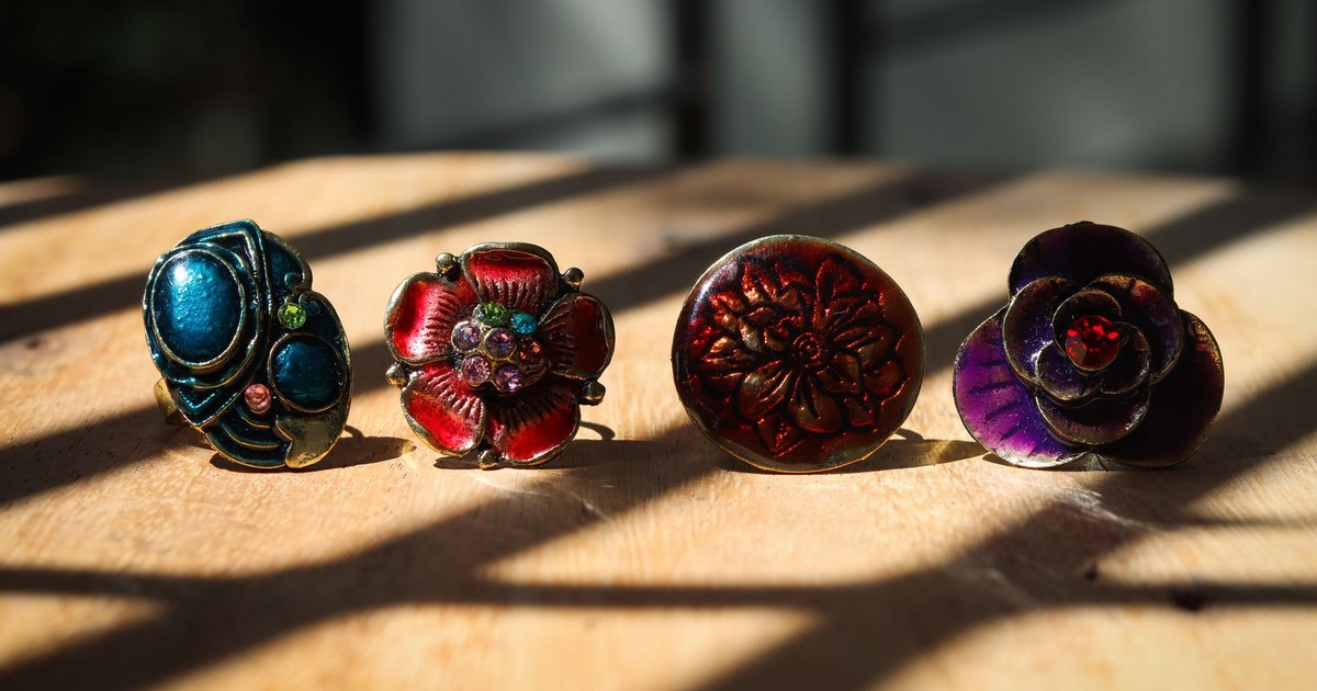 Four vibrant antique rings in bohemian style displayed on a sunlit wooden surface.