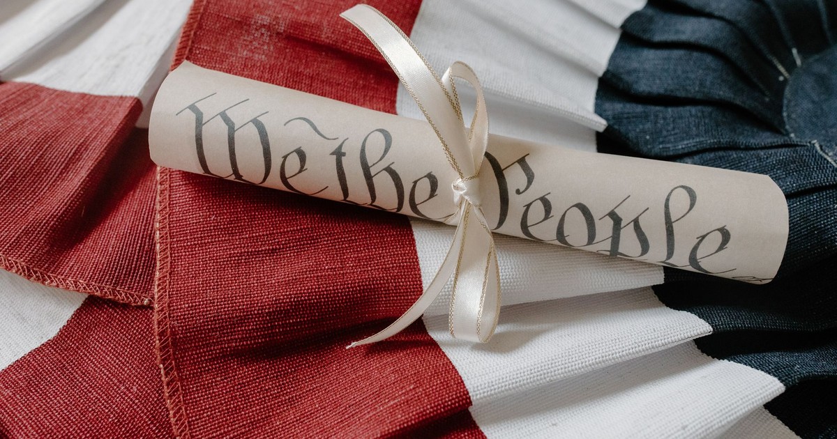 Close-up of a 'We the People' scroll on an American flag cloth background.