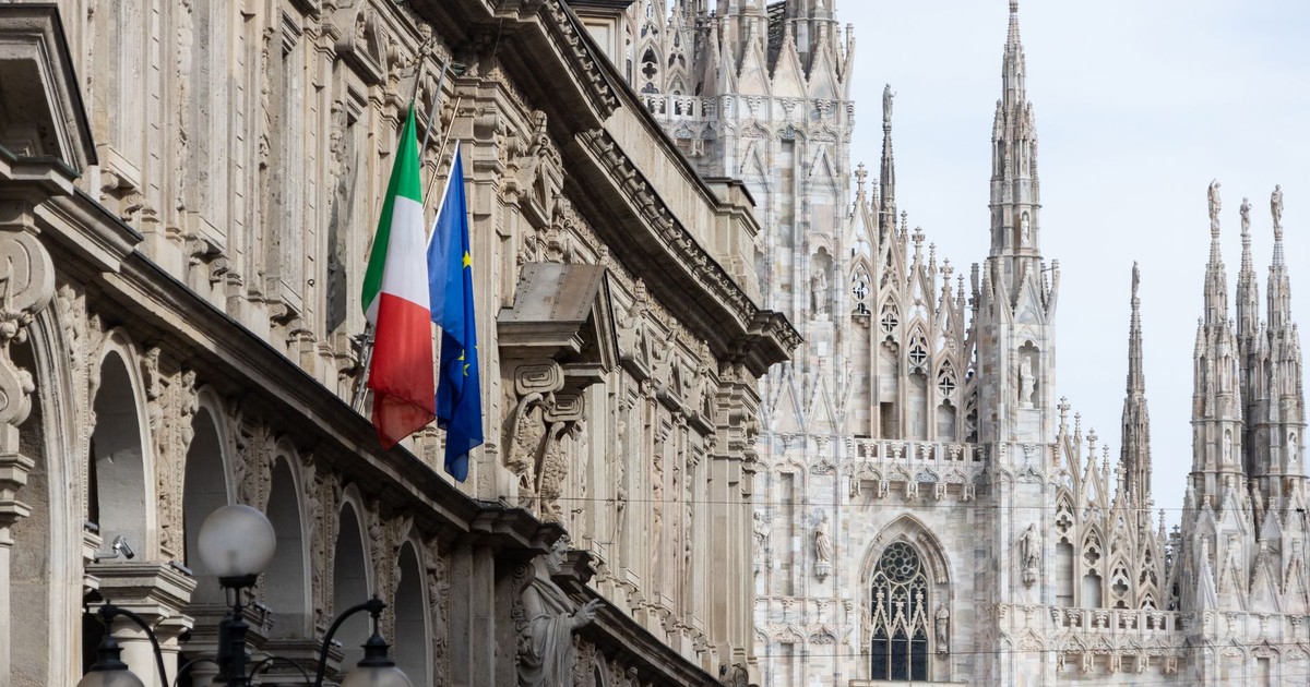 View of the iconic Duomo di Milano with Italian and European Union flags in the foreground.