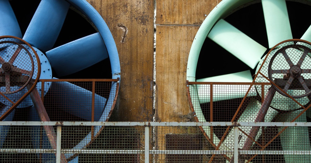 Close-up of large industrial ventilators mounted on an aging building exterior.