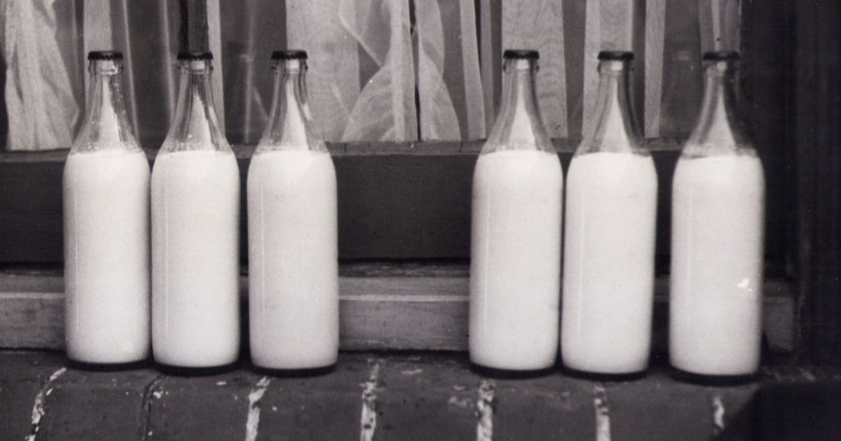 Vintage photo of glass milk bottles on a brick windowsill in monochrome.