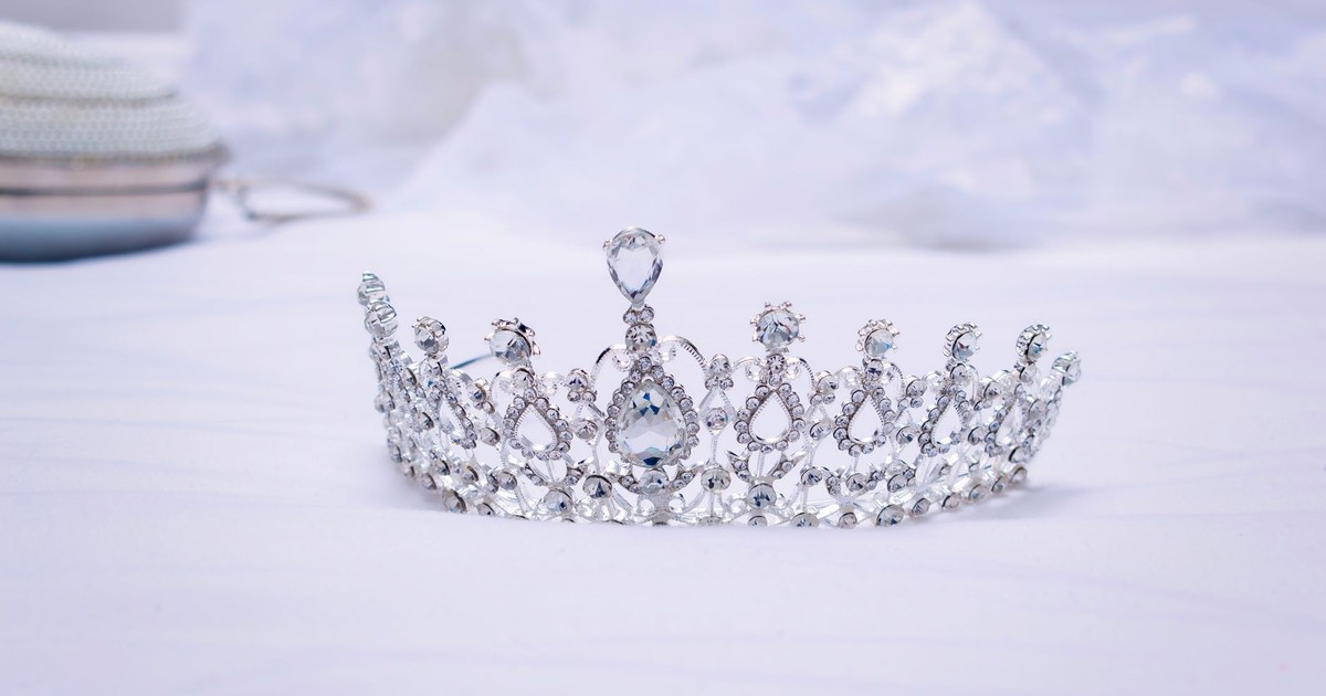 A luxurious diamond-studded crown symbolizing royalty and wealth rests on a serene white backdrop.