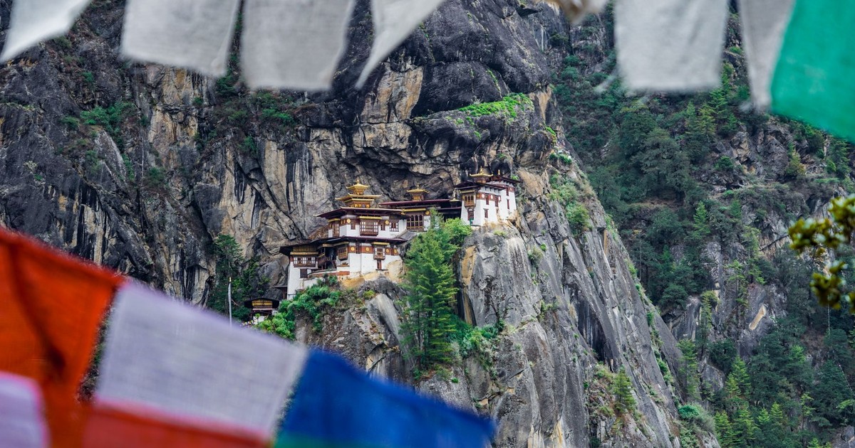 A stunning view of Paro Taktsang Monastery nestled in the cliffs of Bhutan with vibrant prayer flags.