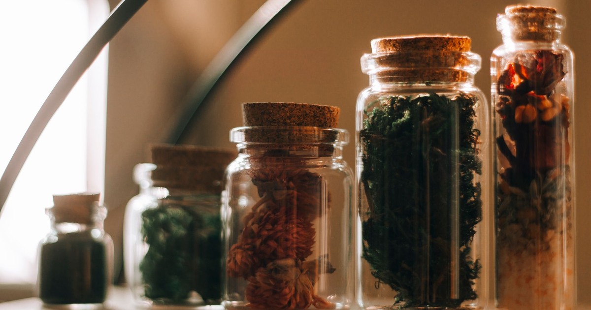 Beautiful glass jars filled with various herbs arranged in warm natural light.