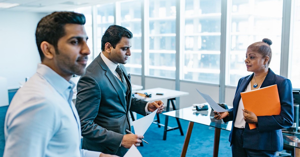 Business professionals discussing documents in a modern office environment.