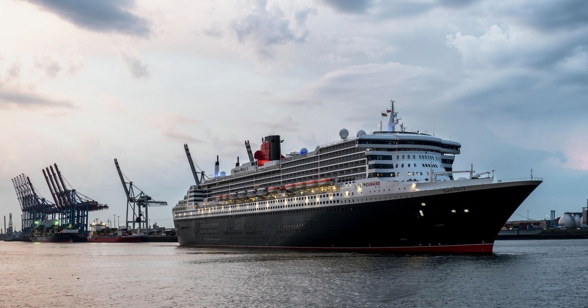 Queen Mary 2 at Hamburg Harbor surrounded by cranes and calm waters under a morning sky.