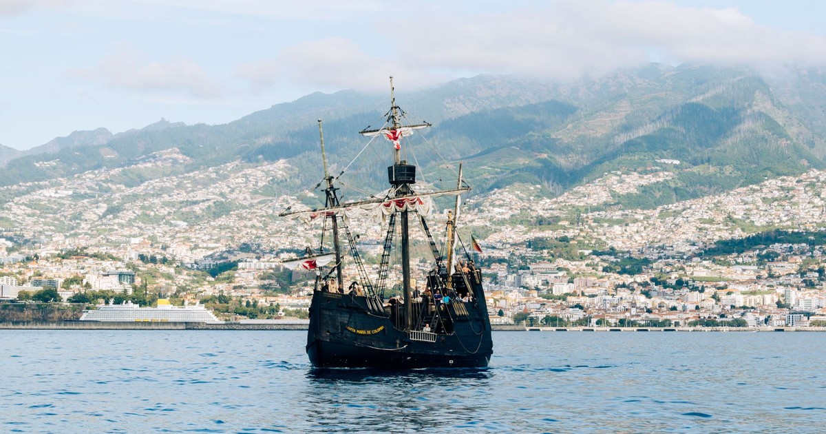 A historic ship sails in Funchal Bay with Madeira's mountains in the backdrop.