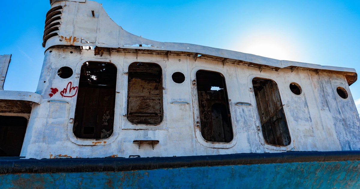 A rusty, abandoned ship rests under a clear blue sky in the Aral Desert, representing the impact of environmental changes.