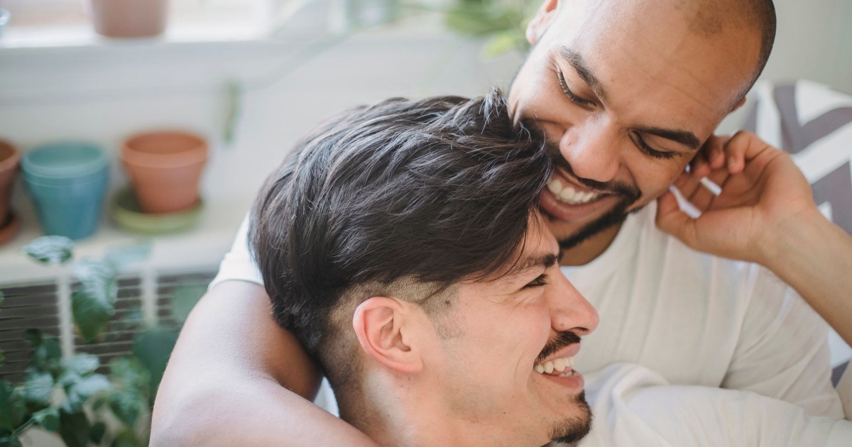 Happy couple embracing and laughing in a bright indoor setting, showcasing love and connection.
