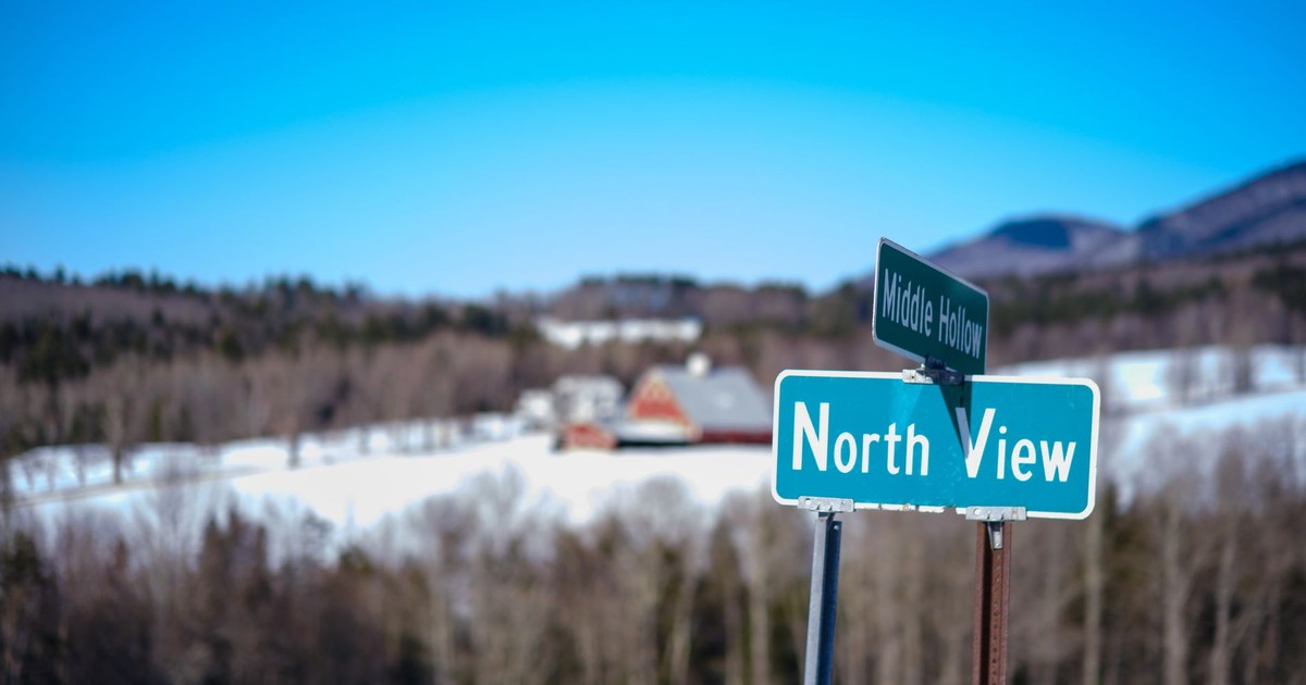 Scenic winter landscape featuring a road sign and rural farmland in Vermont.