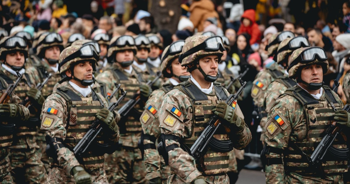 Soldiers in uniform march during a military parade featuring diverse troops and spectators.