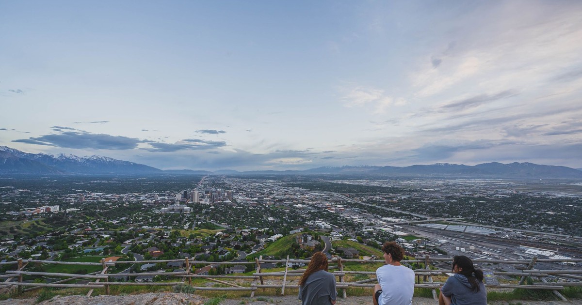 Group of friends sitting on a hill enjoying the panoramic cityscape view.