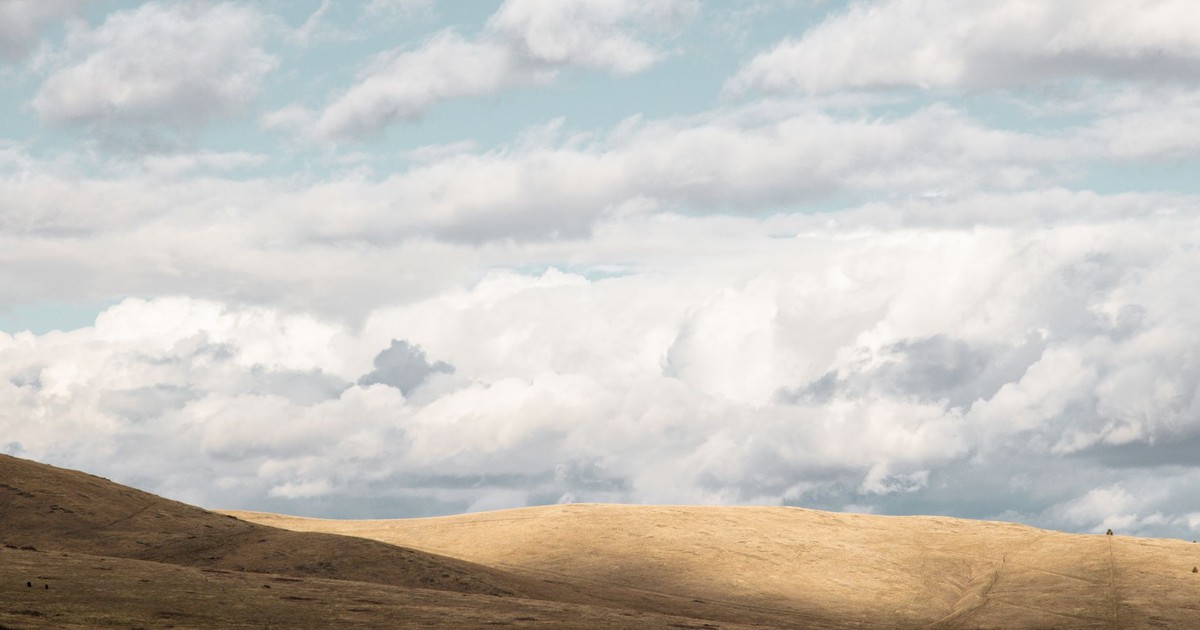 Expansive view of rolling hills and clouds in Montana's landscape, perfect for serene nature scenes.