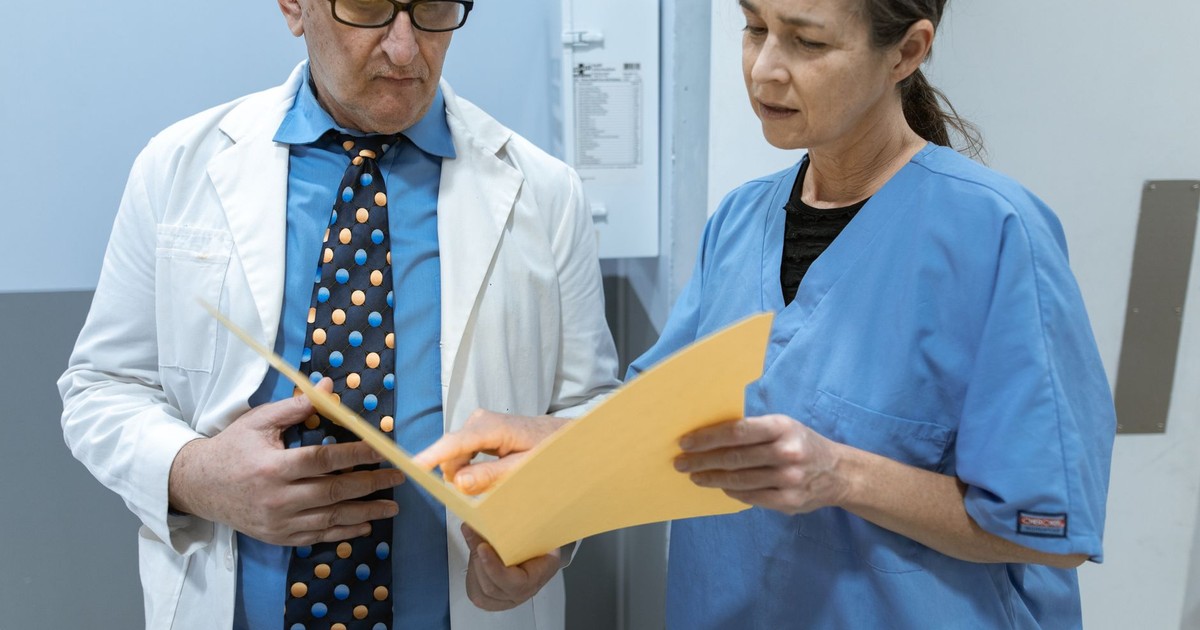 Doctor and nurse examining patient records in a clinical setting.