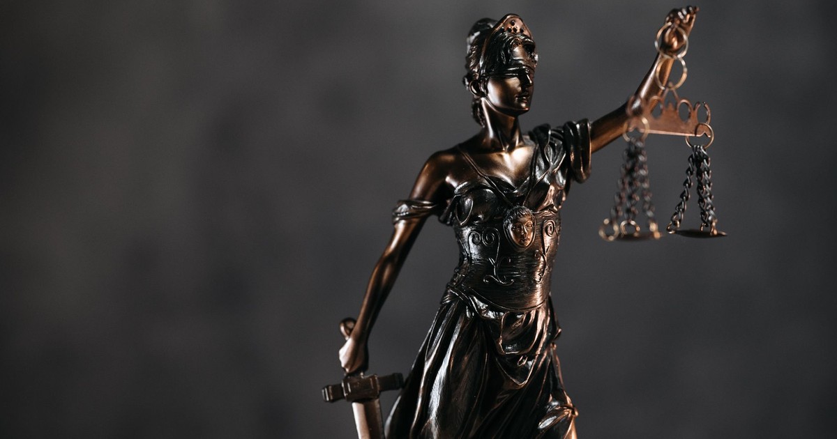 Detailed bronze Lady Justice statue with scales and sword against a dark background, symbolizing law and justice.
