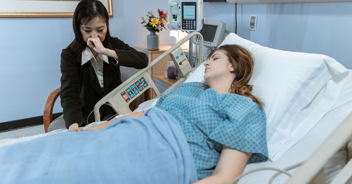 A patient lies in a hospital bed with a caring family member nearby, showing support.