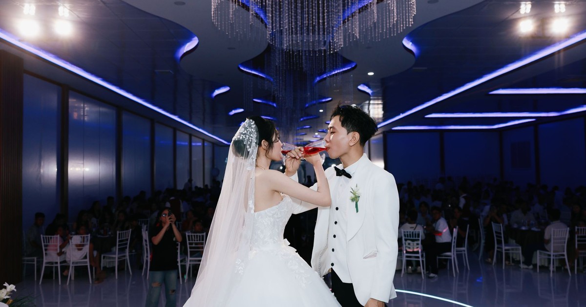 Bride and groom sharing a toast at a beautifully decorated indoor wedding ceremony.