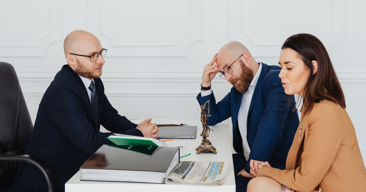 Lawyer consulting couple on divorce settlement in an office setting.