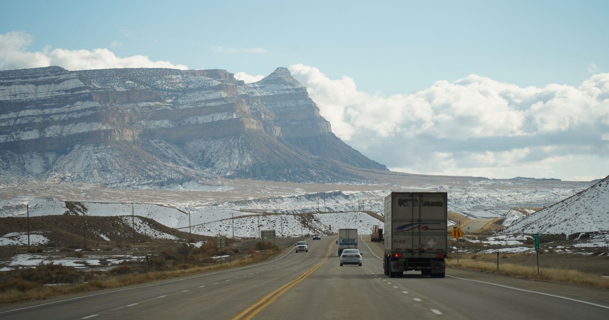 A winter road trip through mountainous terrain with vehicles on a scenic highway.