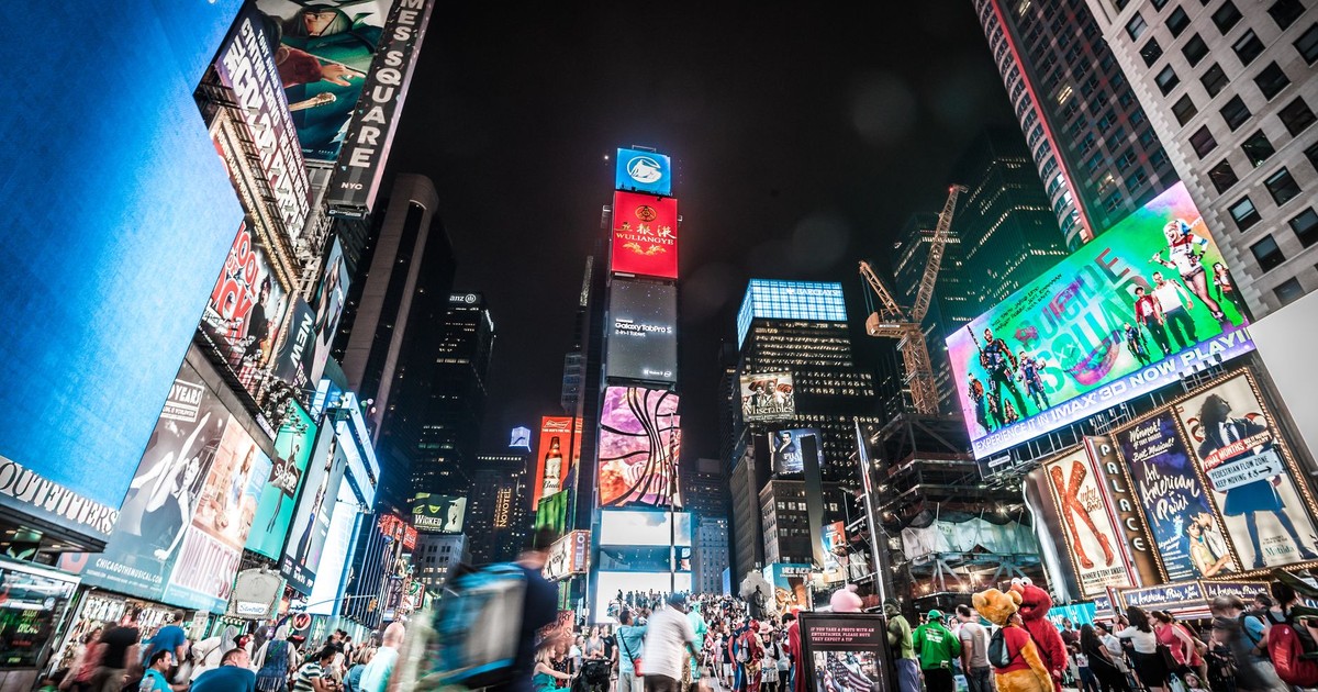 Times Square illuminated at night with bustling crowds and bright billboards in New York City.