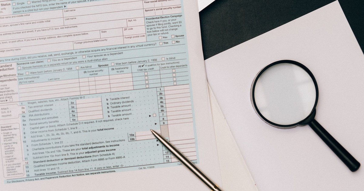 A detailed view of a tax return form with a pen and magnifying glass, perfect for financial themes.
