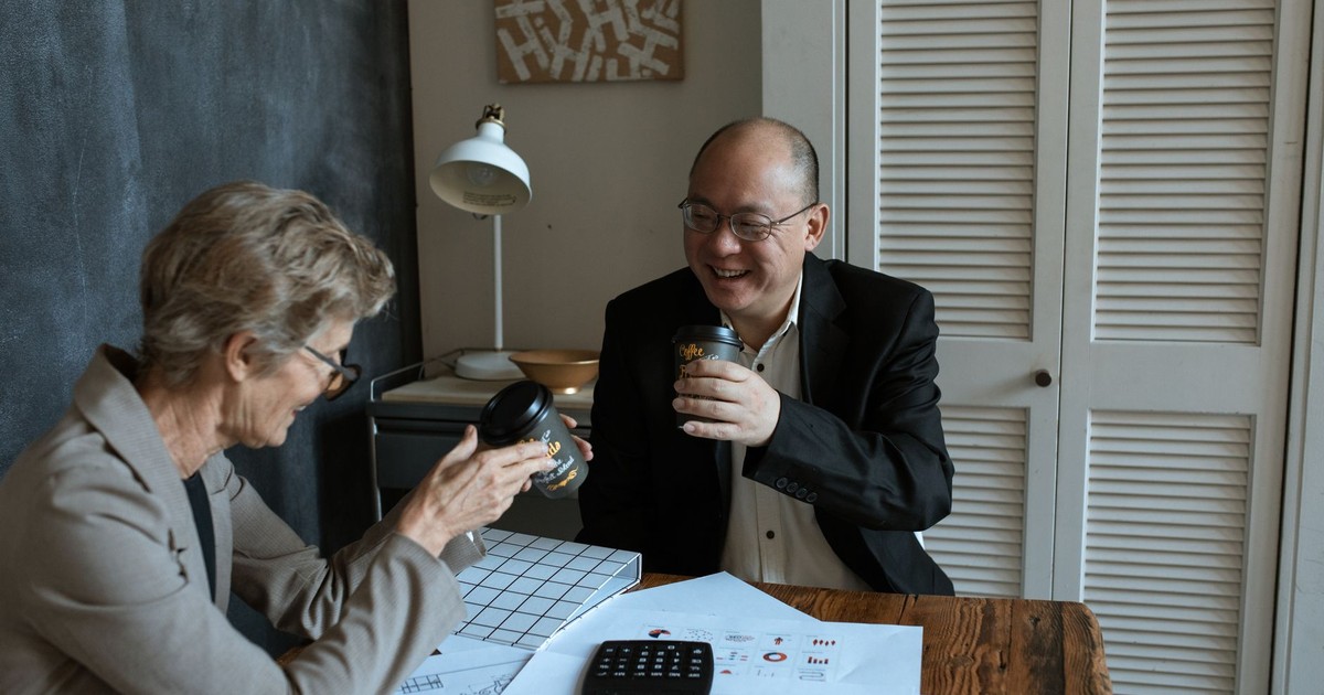 Business professionals sharing coffee and charts at an office table.