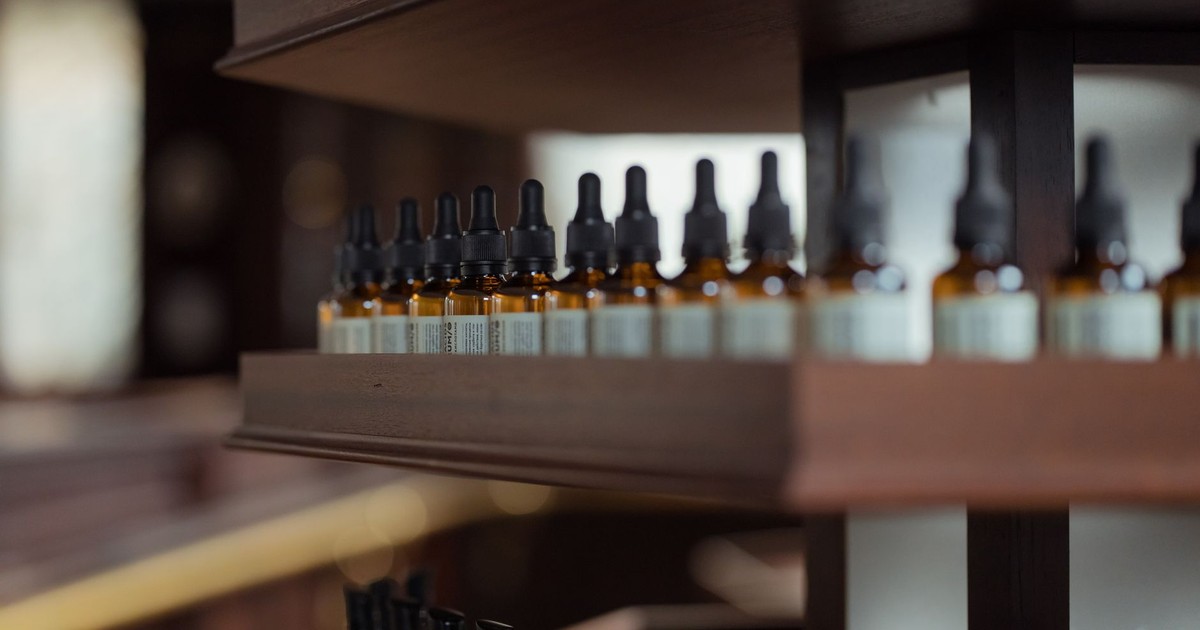Close-up of essential oil bottle droppers on a wooden shelf in a store setting.