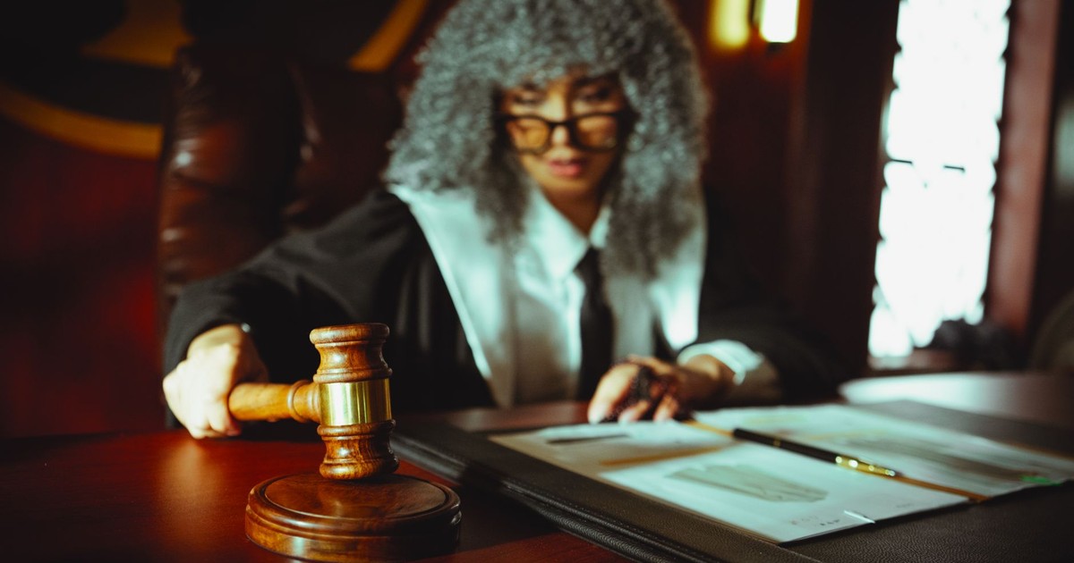 Female judge in a courtroom setting, focusing on legal documents with a gavel.