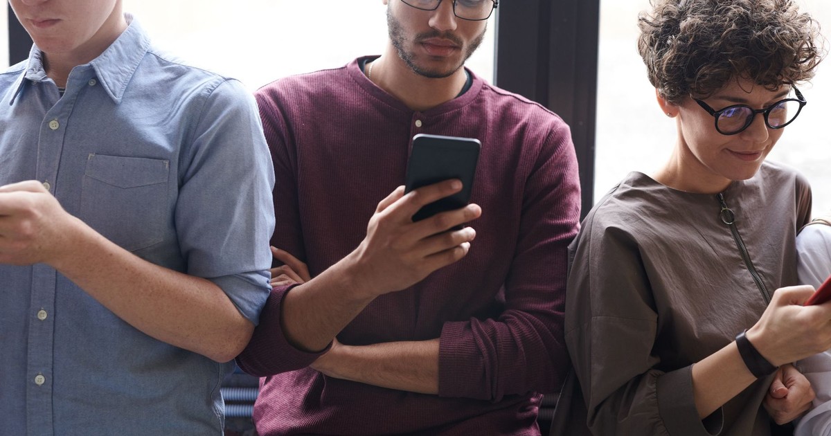A diverse group of people actively using smartphones indoors. Modern technology and social interaction.