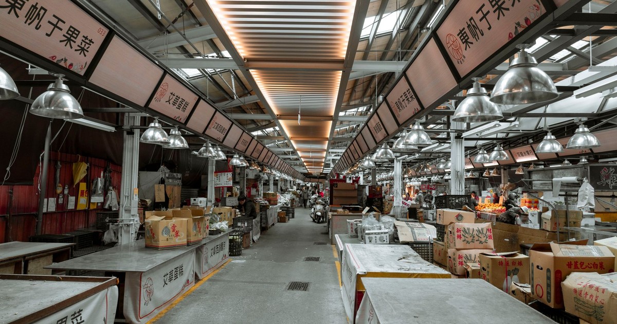 An urban indoor market with empty stalls, showcasing overhead lights and Asian signage.