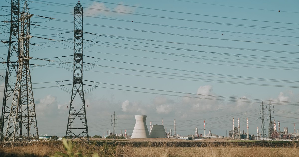 Scenic view of high voltage towers and power plant against a clear sky over dry grassland.