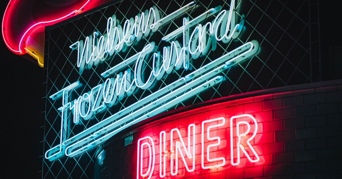 Colorful neon signs illuminate a retro diner at night, creating a nostalgic ambiance.