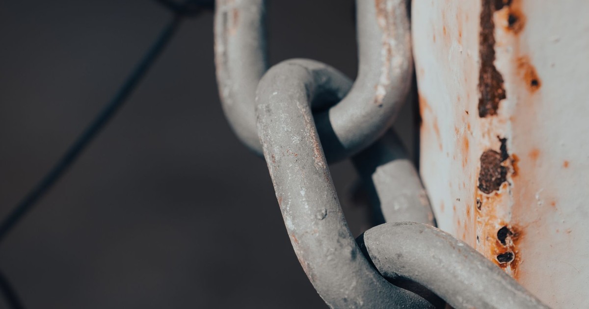 Close-up shot of a rusty metal chain wrapped around a weathered post.