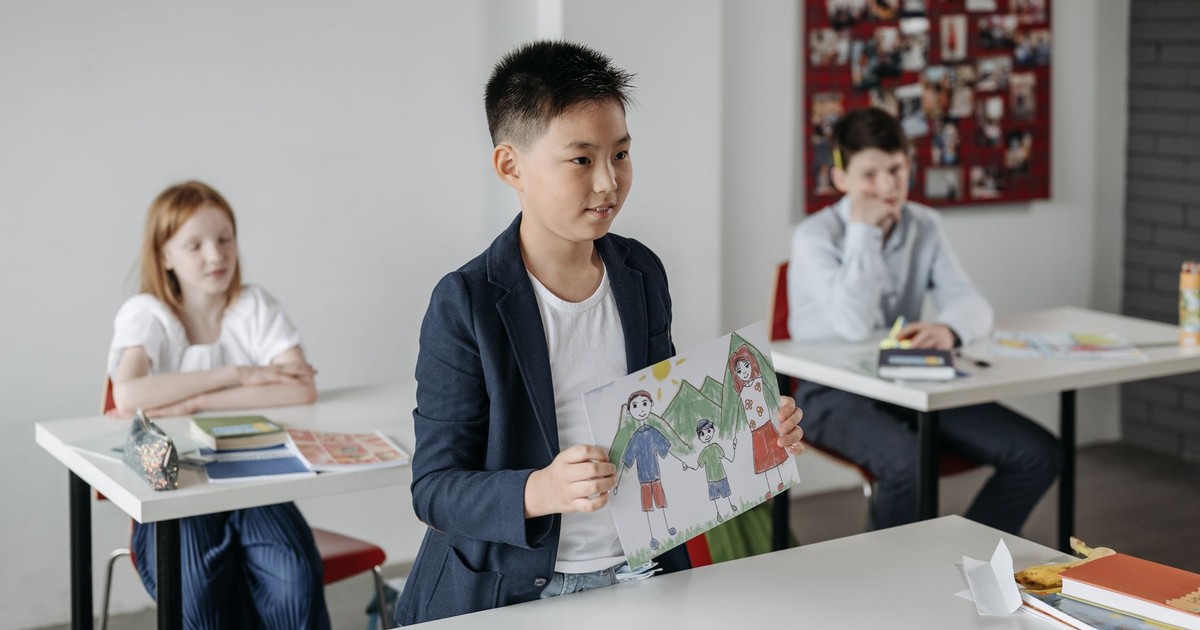 Child showcasing drawing in a classroom setting, focusing on education.